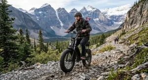 A stylized graphic of a fat tire electric scooter climbing a rugged trail with the Canadian Rockies in the background.