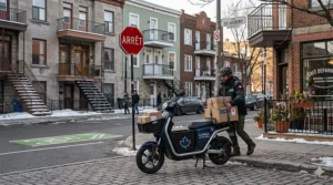 An electric cargo scooter for delivery parked in Montreal, showcasing efficient urban last-mile logistics in Quebec near a stop sign and brownstone stairs.