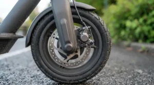 A detailed close-up of the disc brake and front wheel assembly on a single motor electric scooter.
