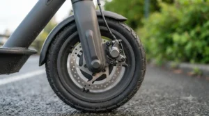 A close-up view of the rear tire and active red safety light on a single motor electric scooter on a city road.