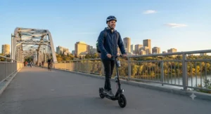 An adult commuter riding an affordable fast charging electric scooter across a bridge in Edmonton.