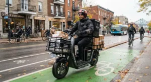 A delivery rider navigating Montreal bike lanes with a heavy-duty extended range scooter and parcel carrier.