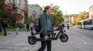 A folding affordable fast charging electric scooter carried by a student near a Montreal university campus.