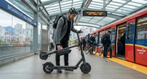 A commuter folding a lightweight medium-range electric scooter before boarding a TransLink Skytrain in Vancouver.
