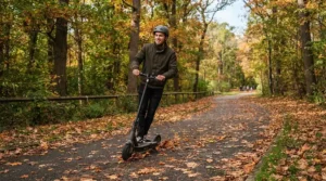 A student cruising on a speed limited electric scooter along a scenic autumn park trail